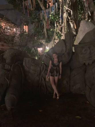 Writer stands in front of a mock Asian ruin of a dragon at Disney's Animal Kingdom Park. It is night. She wears a black romper and sandals and smiles at the camera.
